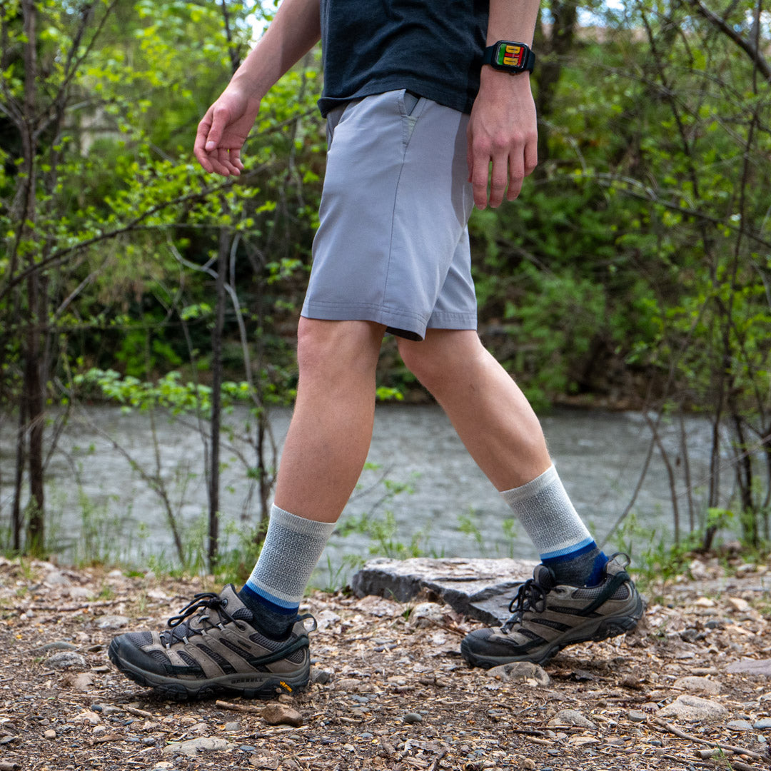 man wearing blue crew socks and hiking by a river